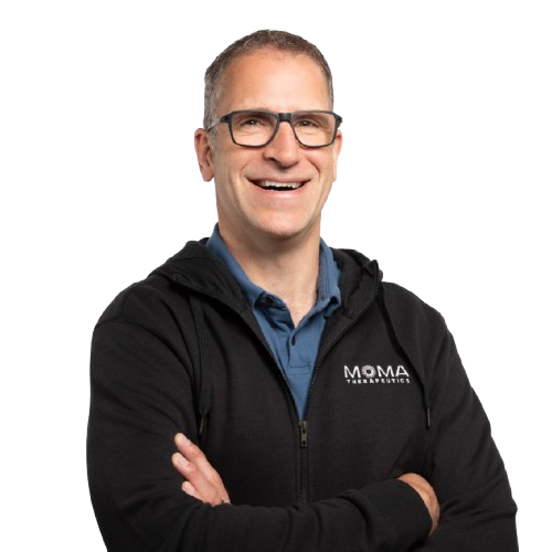 Smiling man with glasses wearing a black zip hoodie with MOMA Therapies logo and arms crossed.